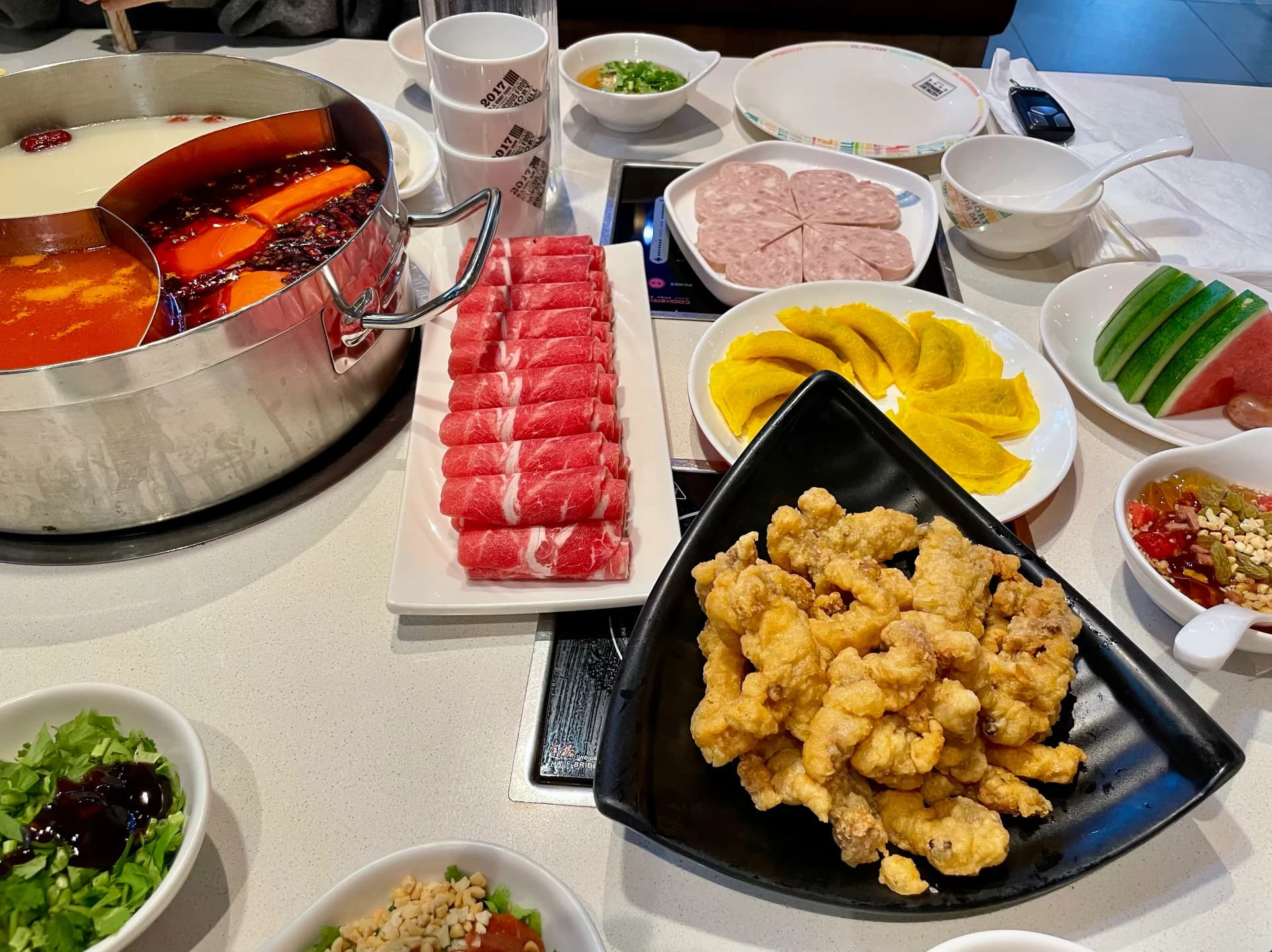 Divided hot pot with sliced meat and side dishes at Memory Tongue Chatswood